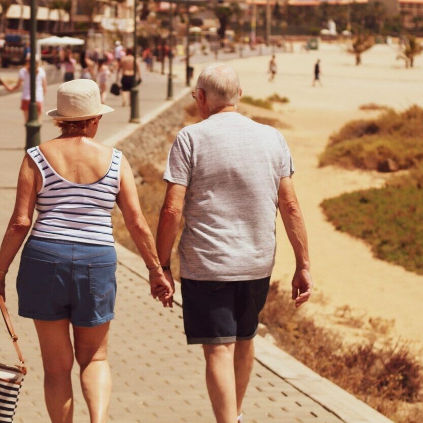 man and woman walking on road while holding hands